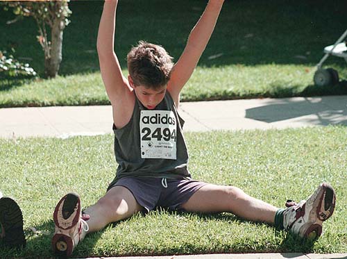 мальчик в майке и спортивных трусах делает зарядку, гимнастику - разминается в спортивной одежде